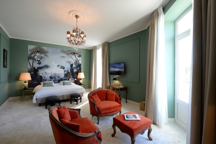 Chambre lit double tête de lit paysage et petit coin salon fauteuils rouges