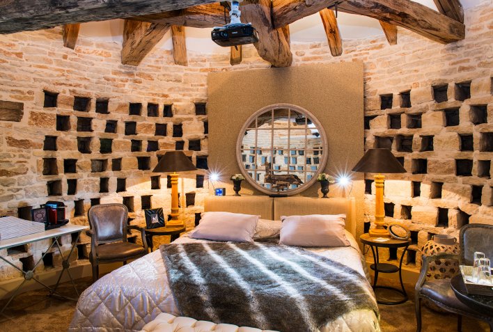 Chambre installée dans un ancien pigeonnier avec perites niches tout autour et miroir à la tête du lit