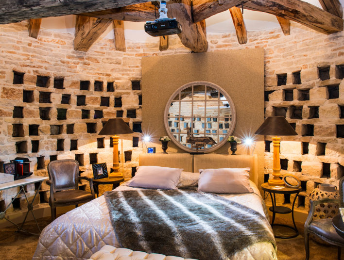 Chambre installée dans un ancien pigeonnier avec perites niches tout autour et miroir à la tête du lit