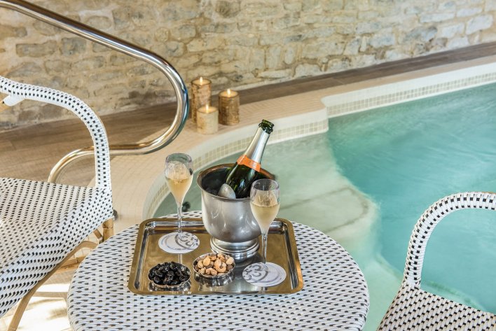 Bouteille de Champagne avec coupes servies sur une table près d'un jacuzzi privatif