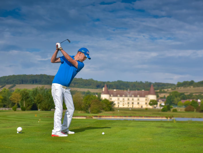Joueur expérimenté amorçant son swing sur le green de l'Hôtel Golf du Château de Chailly en Bourgogne