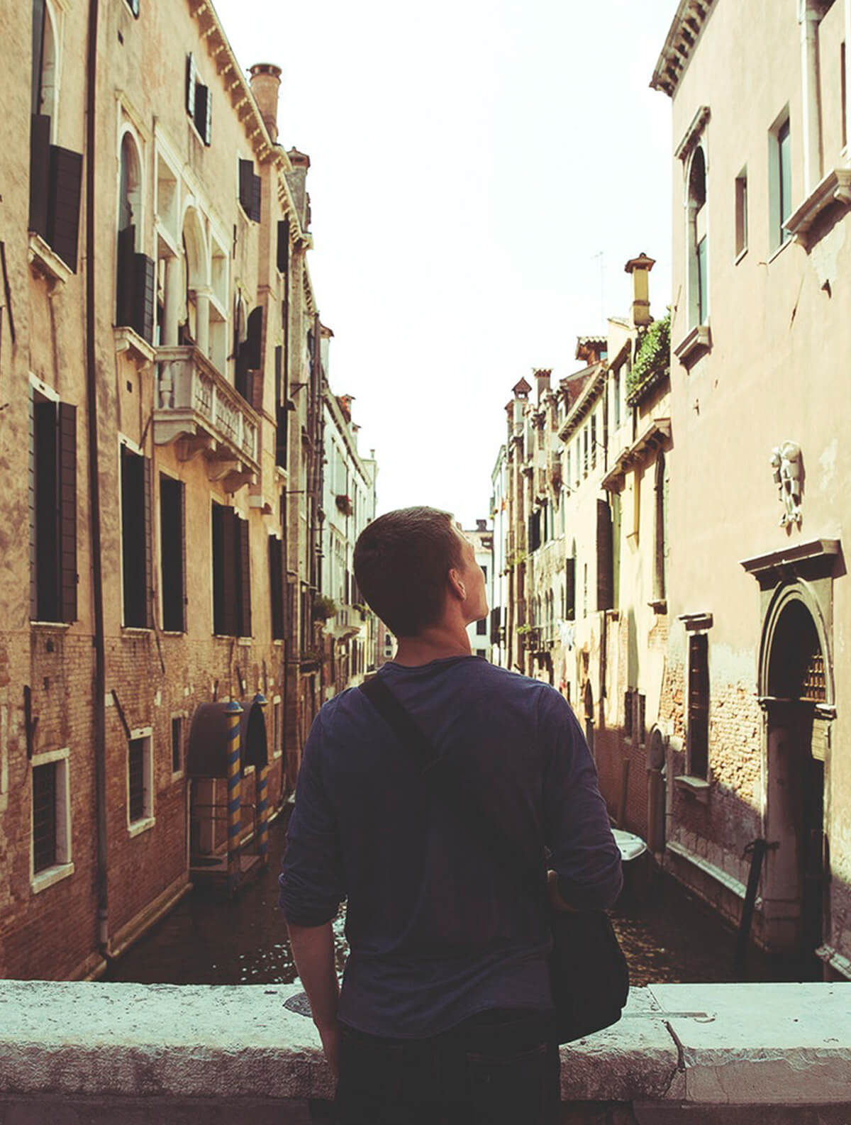 Jeune homme de dos dans la rue regardant des immeubles