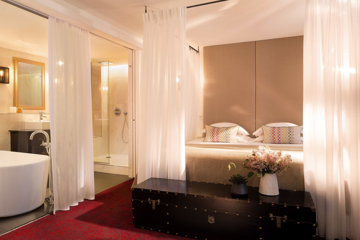 Spacieuse chambre à l'ambiance romantique avec coffre au pied du lit, baignoire et grand douche, lit king size