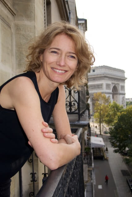 Femme accoudée à son balcon avec une vue sur l'arc de triomphe