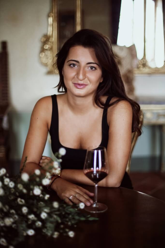 Femme brune accoudée à une table devant un bouquet de fleur
