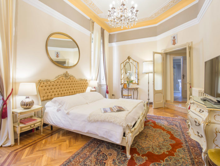 Chambre spacieuse décorée à l'italienne avec tête de lite capitonnée, miroirs, parquet