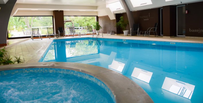 Spa à remous et piscine intérieure avec vue sur jardin paysager
