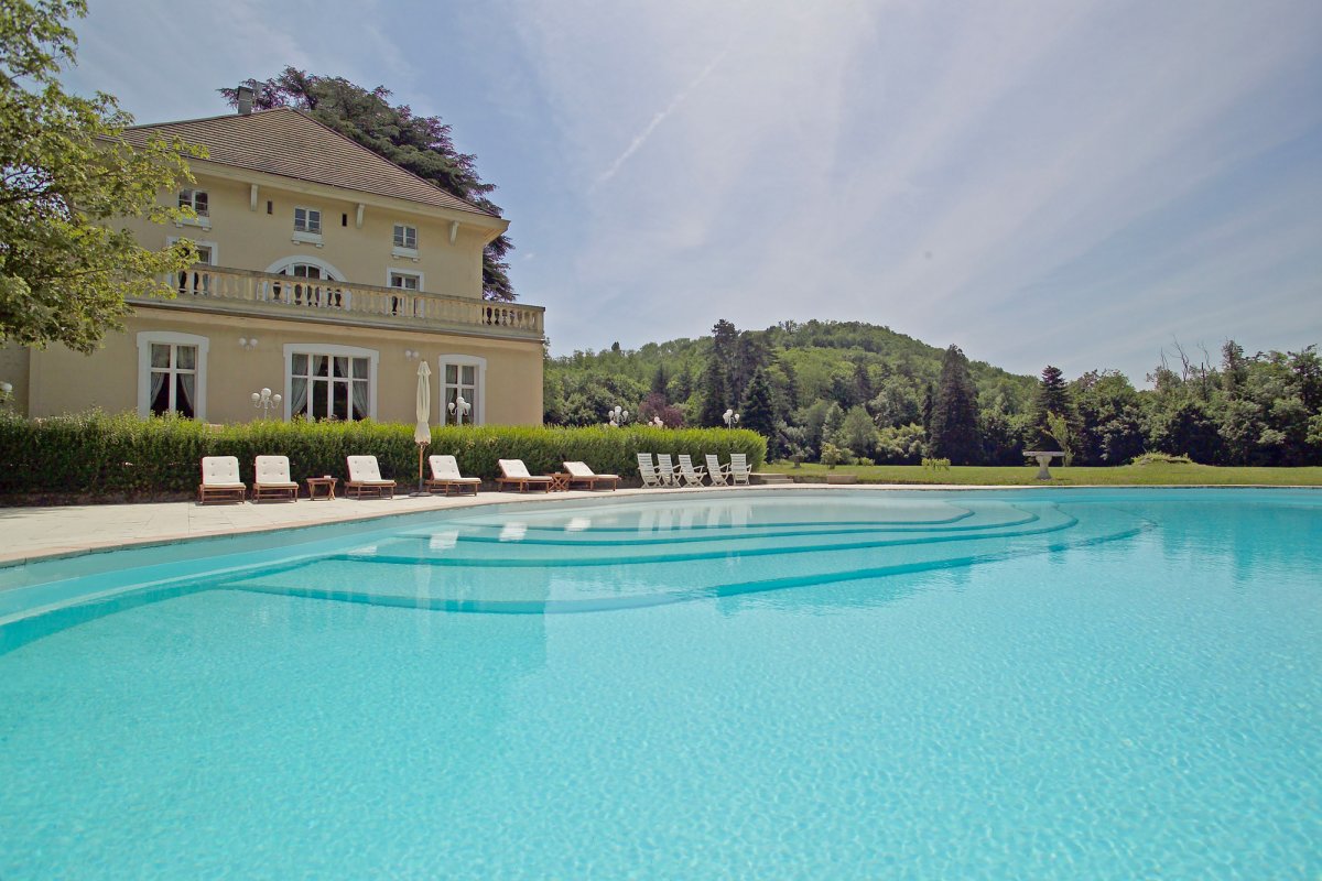 Immense piscine extérieure entourée d'une terrasse carrelée ameublée de transats et chaises longues