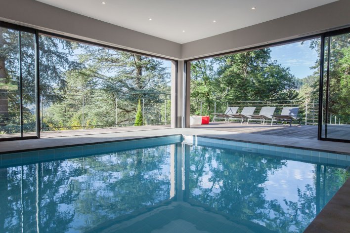 Piscine intérieure donnant sur une forêt de pins.