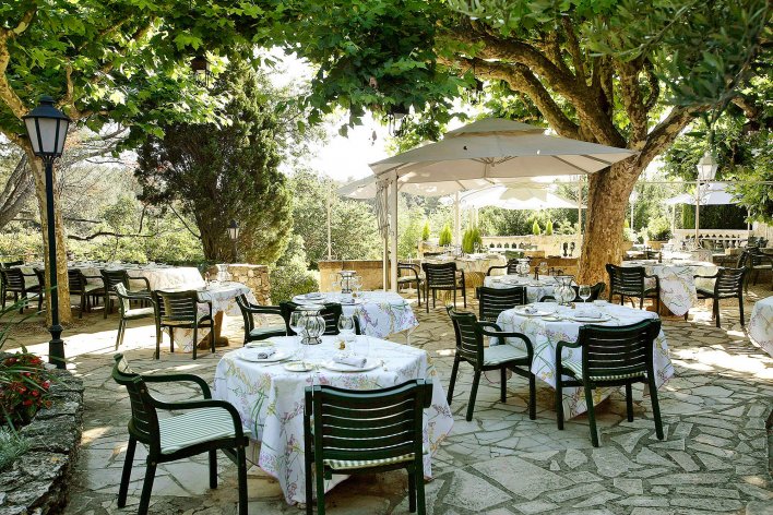 Terrasse provençale avec tables dressées à l'ombre du feuillage.