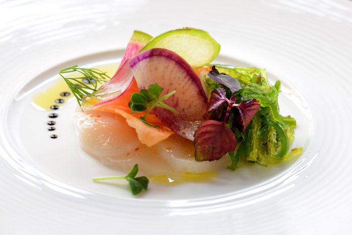 Plat à base de légumes et noix de Saint-Jacques dressé à la manière d'un restaurant gastronomique.