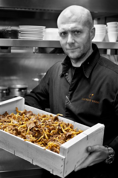 Portrait du chef Laurent Rigal tenant une caisse remplie de champignons.