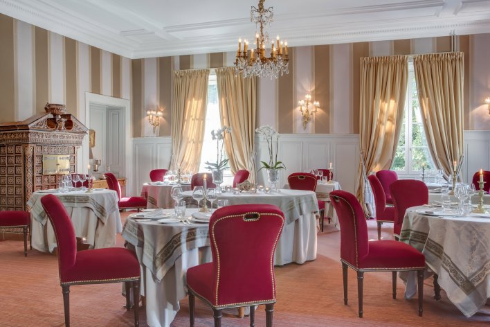 Salle de restaurant chic décoré avec des tentureset des fauteuils en velours rouge.