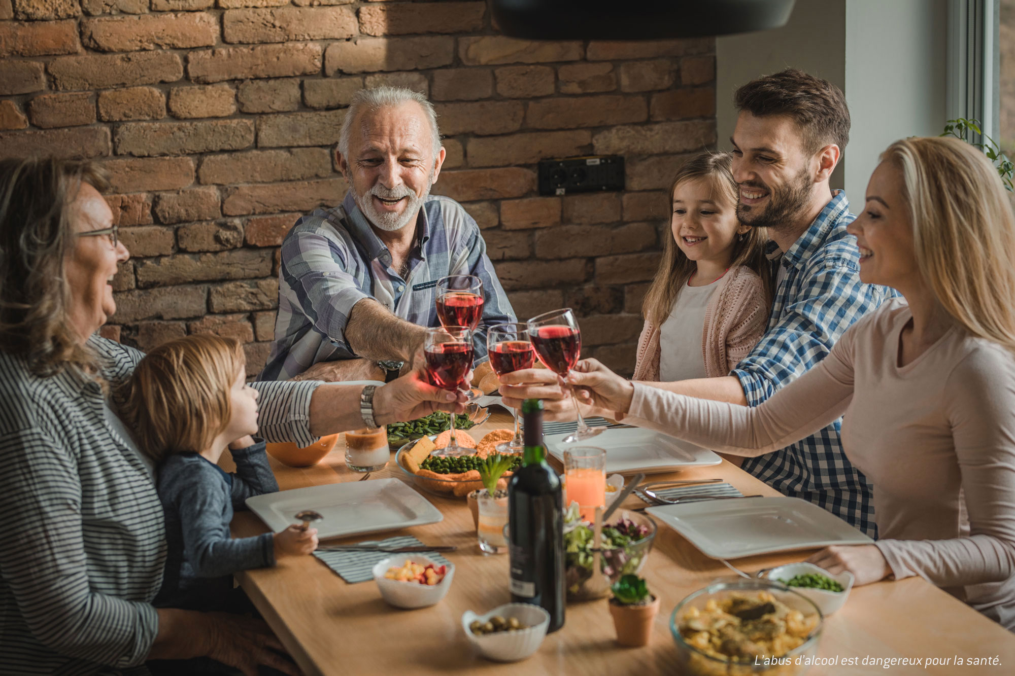 Famille en train de déjeuner et de trinquer tous ensemble à table.