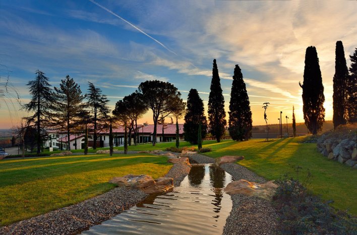 Vaste parc arboré en Italie avec cours d'eau traversant la propriété au coucher du soleil.