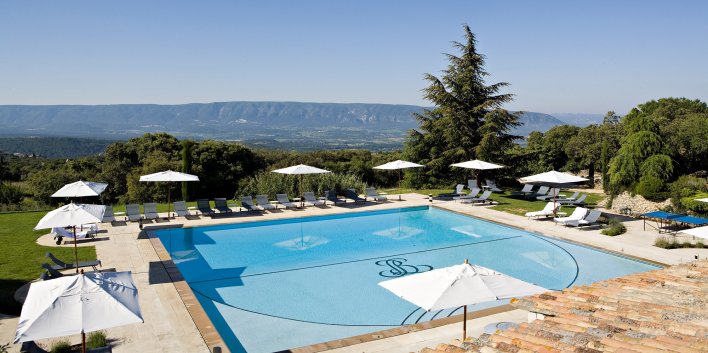 VAste piscine extérieure entourée de transats avec vue sur les montagnes.