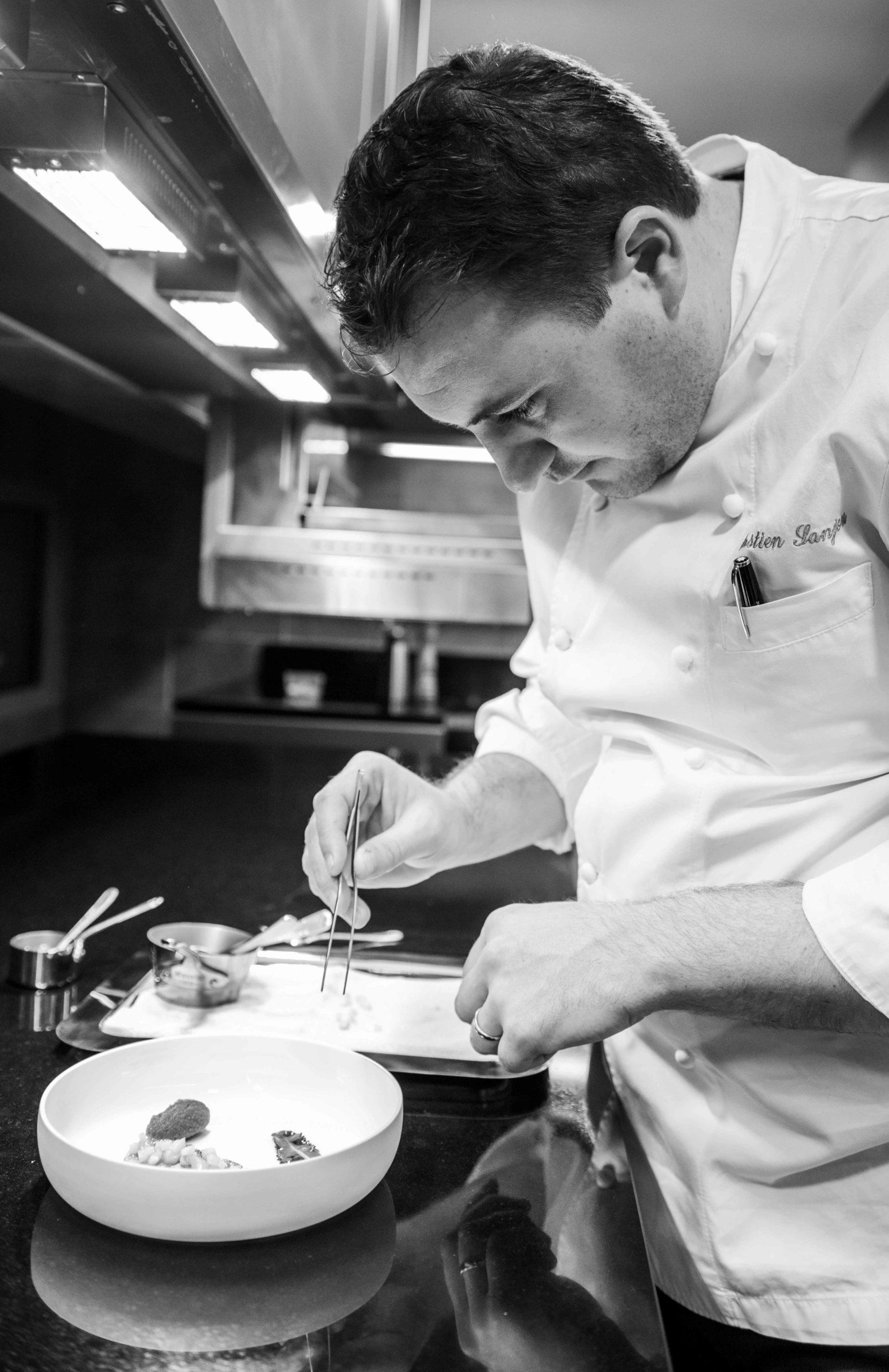 Chef en veste dans sa cuisine prépare un plat