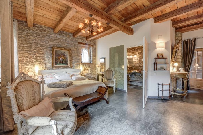 Chambre avec poutre apparente et mur en pierre