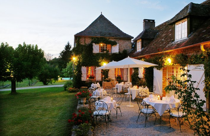 Terrasse avec parasole blanc et bâtisse en pierre