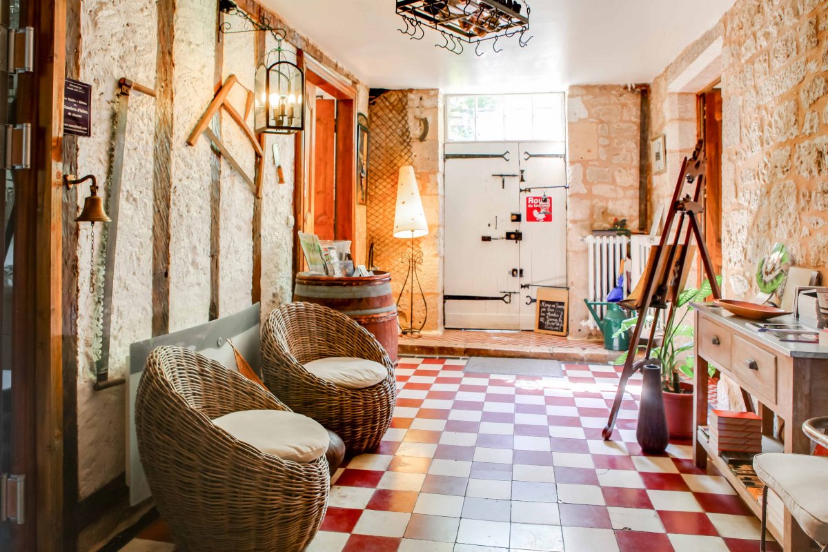 Entrée avec mur en colombage, sol carreaux rouge et blanc et fauteuils en osiers