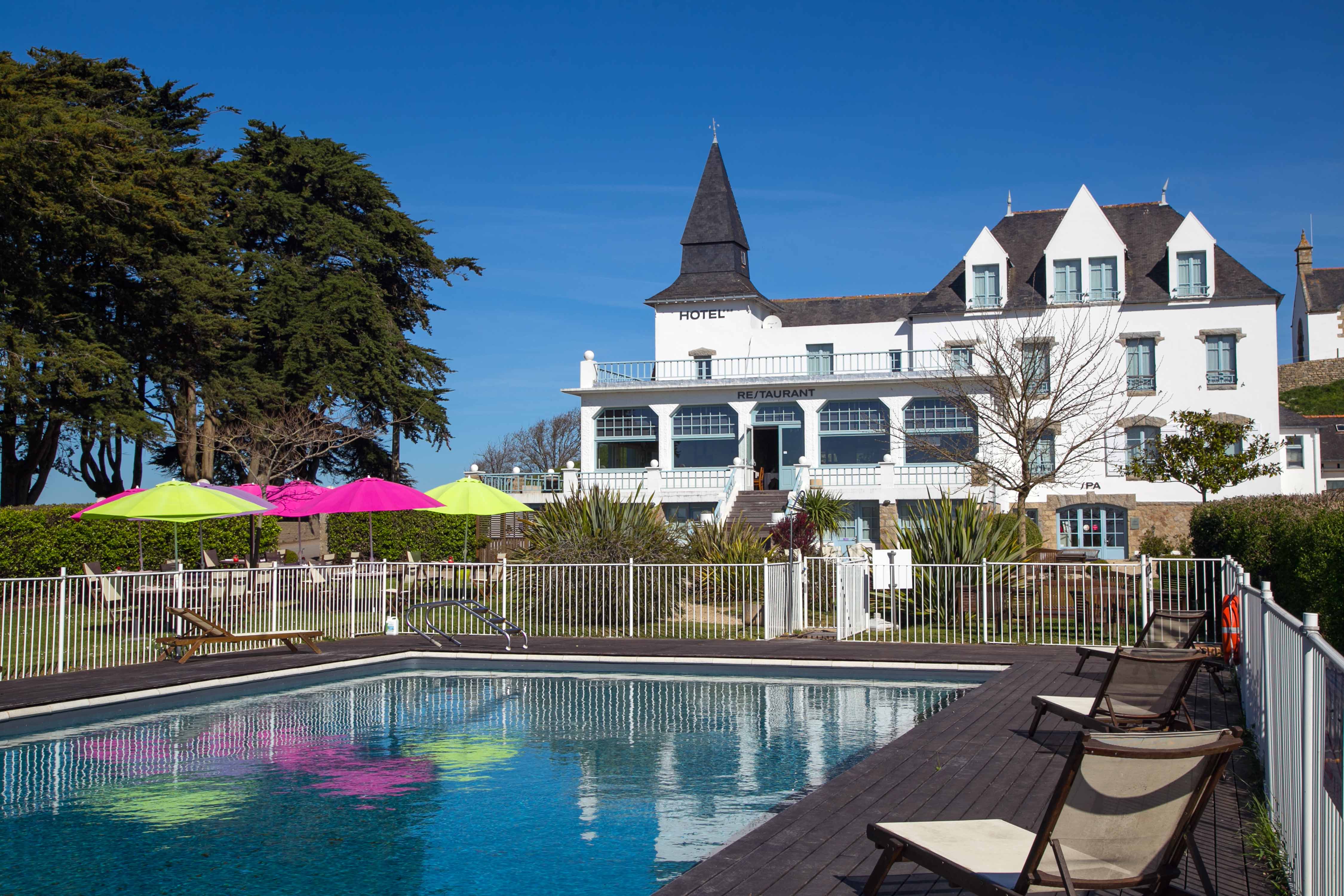 Grande piscine avec transat, devant grand hôtel avec restaurant