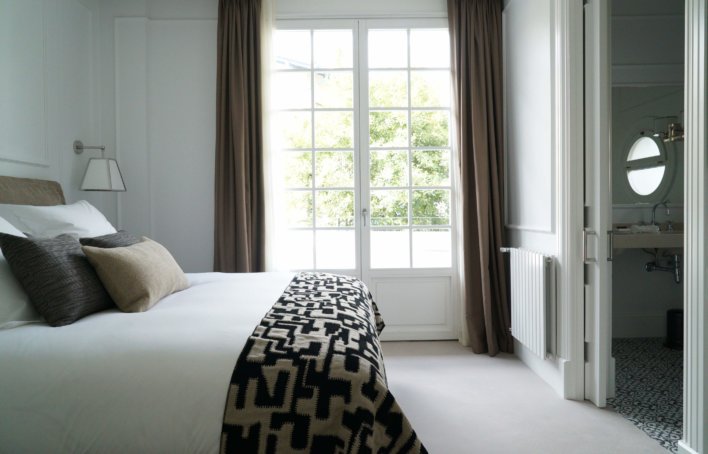 Chambre lit double ton neutre et grande porte fenêtre