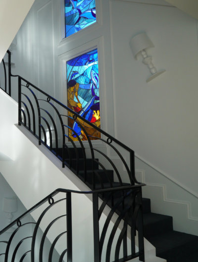 escalier blanc, rembarre fer forgé noir et vitraux aux murs