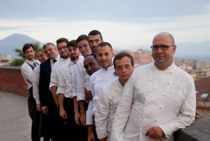 Personnel d'un restaurant photographié devant le Vésuve au loin.
