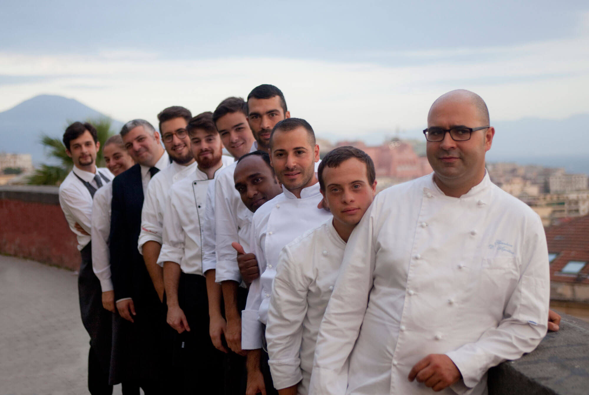 Personnel d'un restaurant photographié devant le Vésuve au loin.