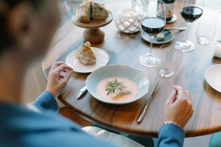 plat de langoustines sur table dressée avec miche de pain et verre de vin rouge