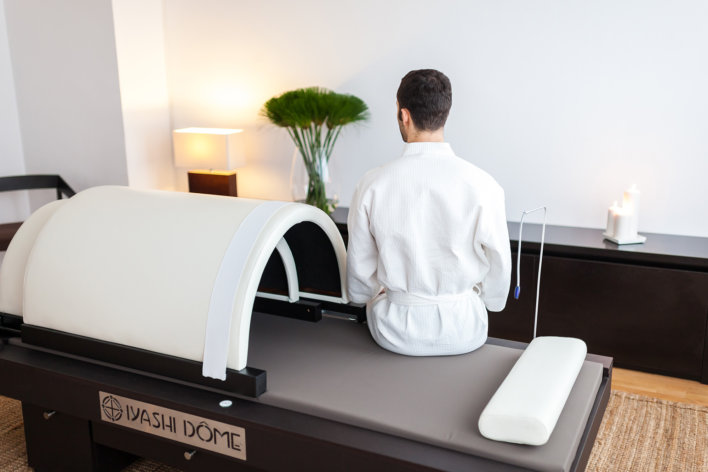 Homme en peignoir blanc sur un banc de soin spa