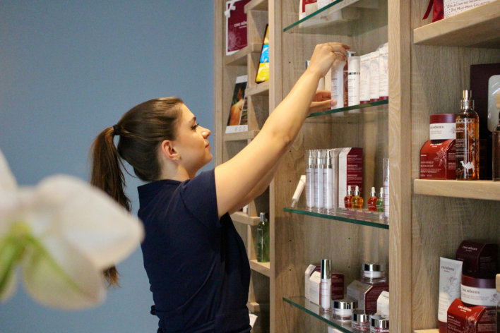 Praticienne spa qui réorganise les produits dans une étagère