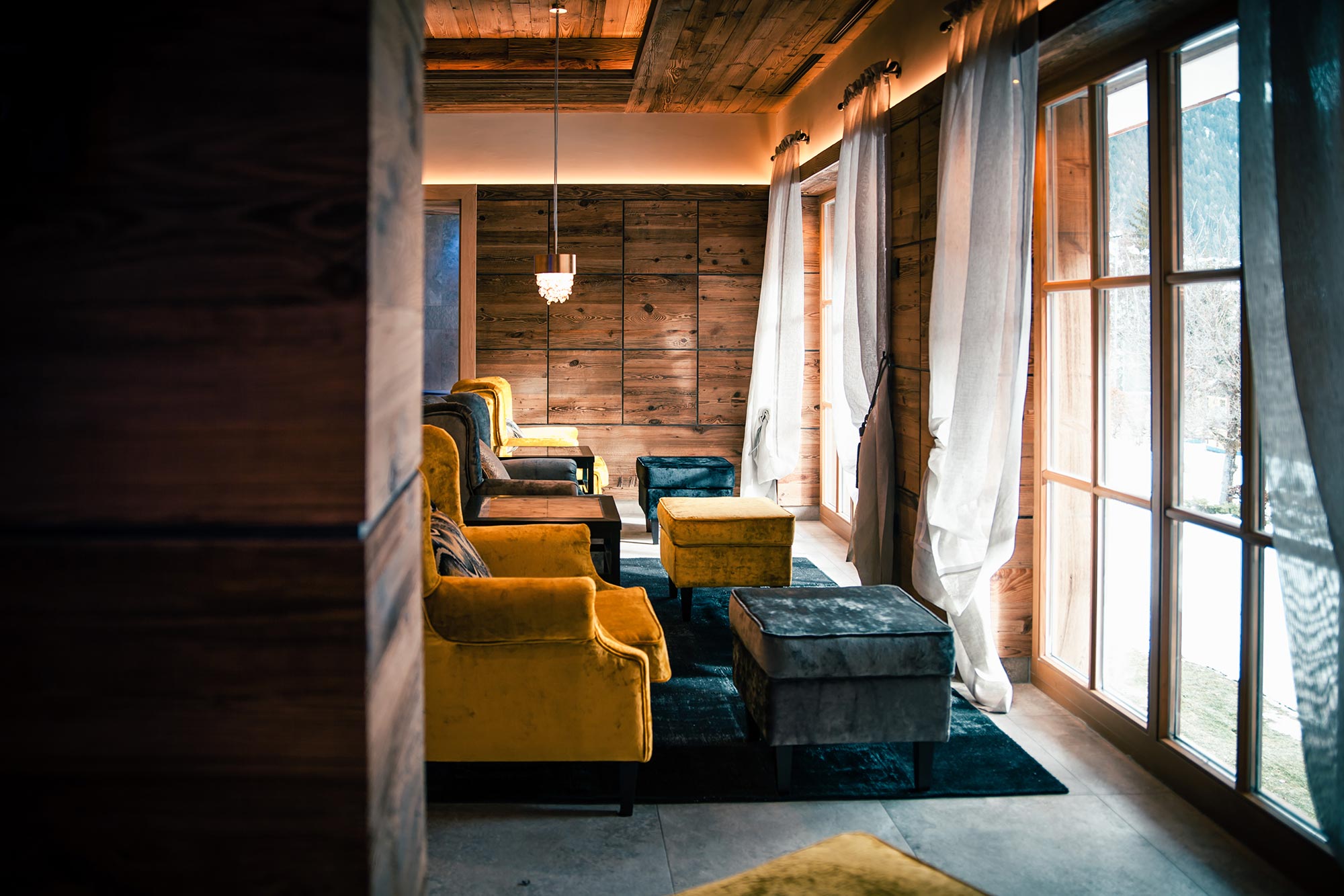 Salon fauteuil jaune et bleu devant des fenêtres avec vue neige
