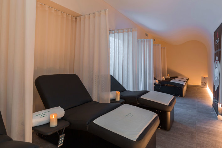 Salle de repos en spa, banc de repos noir séparés par des rideaux blancs