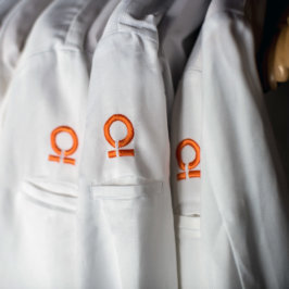 Détail sur épaule de veste de cuisinier brodée d'un oméga orange