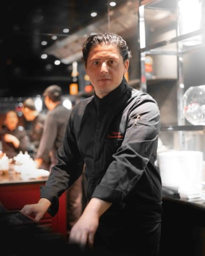 Portrait d'un chef devant un bar de restaurant, en veste noir