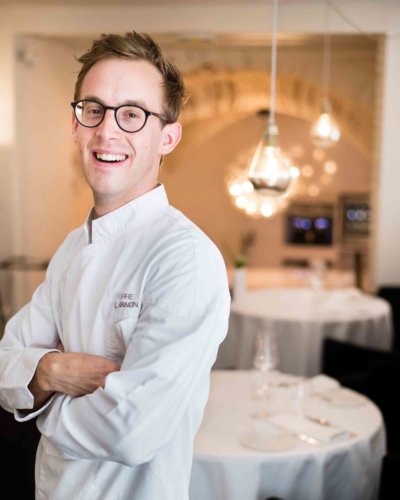 Portrait chef en veste blanche et dans sa salle de restaurant