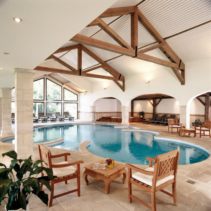 Espace détente avec deux chaise et une petite table d'un coter de la piscine et deux autres chaise avec une petite de l'autre coter de la piscine
