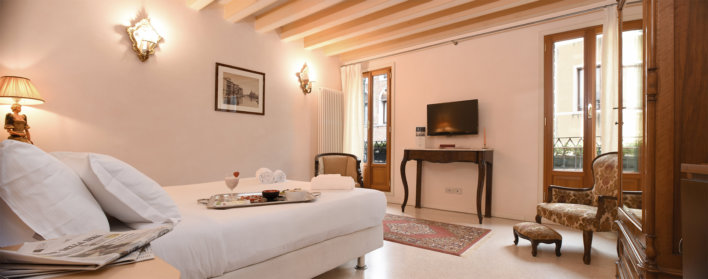 Chambre prise en photo en diagonal avec un lit double et un plateau de petit-déjeuner sur le lit