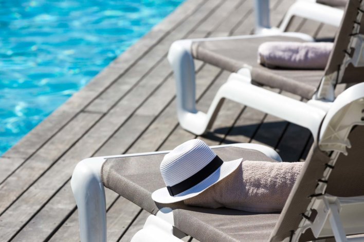 Détail de transat en bord de piscine avec canotier