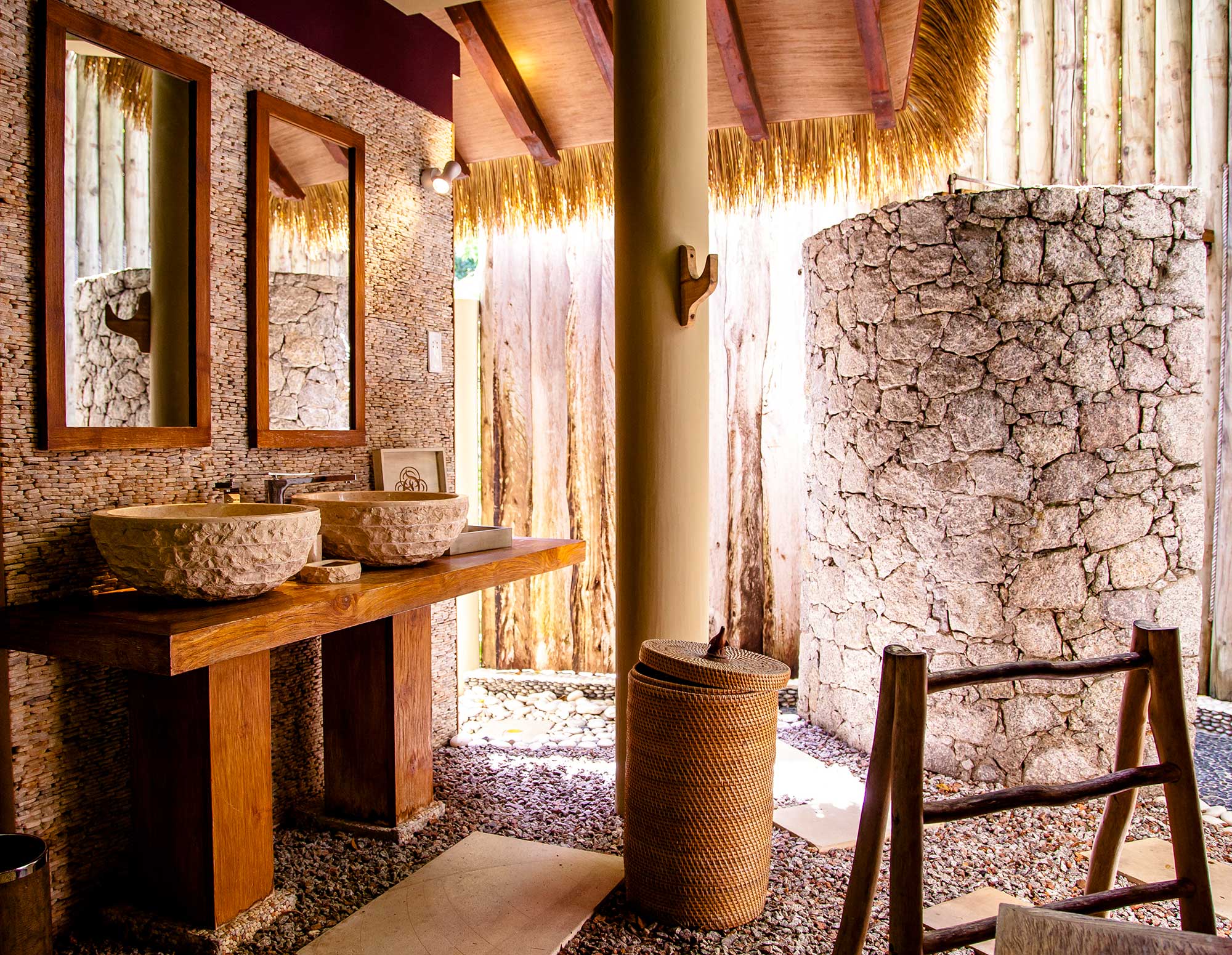 Salle de bain en matérieaux bruts : pierres, bois, galets et toit naturel