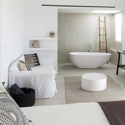 Suite avec salle de bain ouverte, baignoire centrale, décoration matériaux naturels
