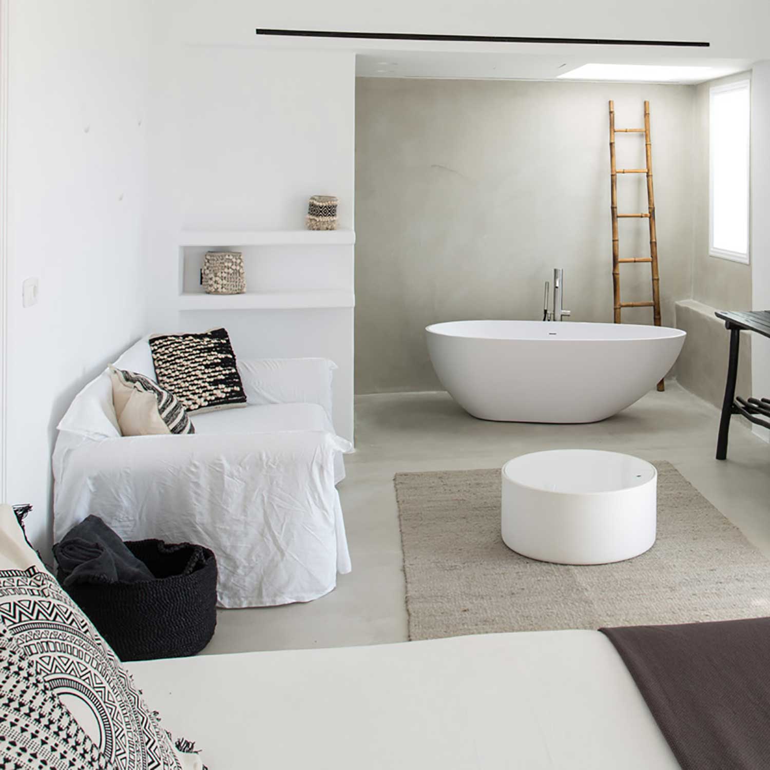 Suite avec salle de bain ouverte, baignoire centrale, décoration matériaux naturels