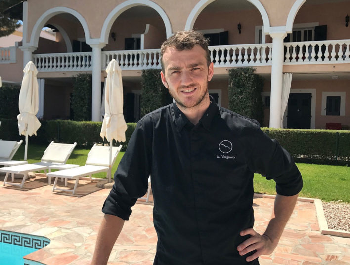 Chef en veste noir, arrière plan hôtel avec alcôves et piscine sur le côté gauche