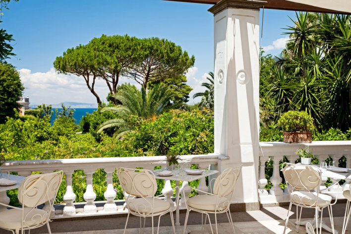 Photo de la belle terrasse avec une magnifique vue sur l'extérieur, on y trouve sur cette photo une trois table, dont une table au milieu avec deux chaises