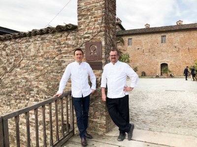 Photo d'un duo de chefs en veste de cuisine blanche à l'entrée d'un domaine
