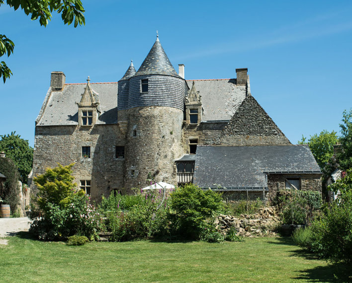 Façade de type médiéval avec jardin tout autour.