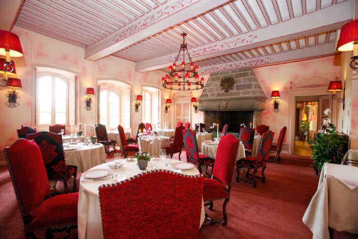 Salle de restaurant typique d'un château avec chaise capitonnée rouge et table nappée blanc