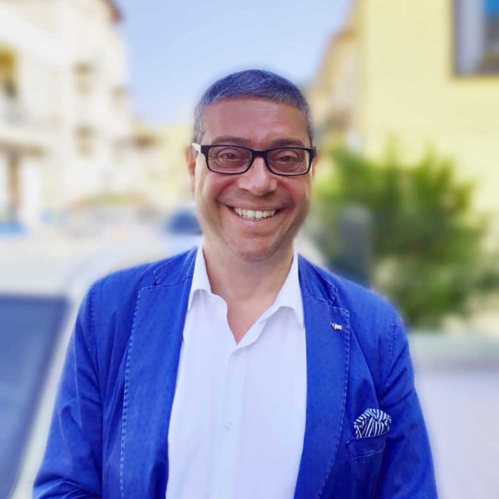 Portrait d'un homme en blazer bleu et chemise blanche, arrière plan flouté