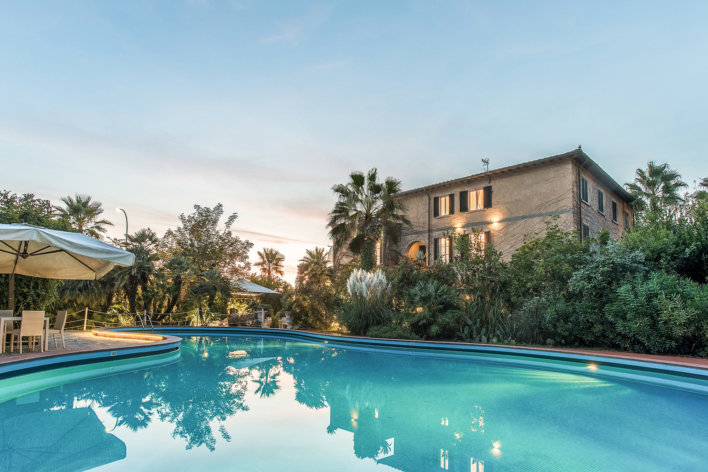 Piscine avec vue sur villa typique italienne et végétation tropicale